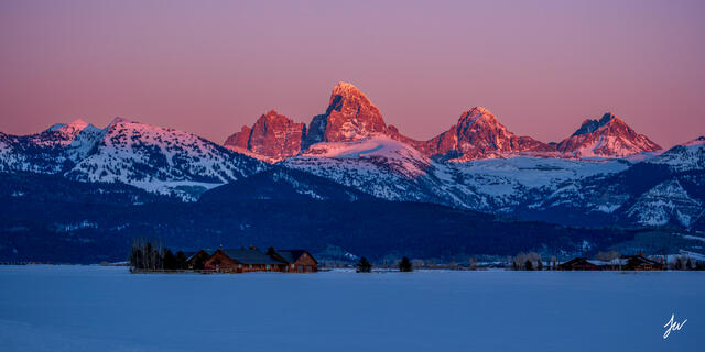 Sunset over the Grand Teton mountains viewed from the Idaho side, with vivid colors and rugged peaks in the distance.