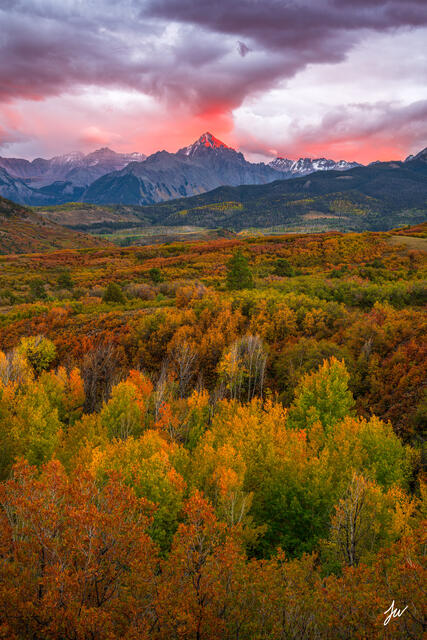 Mount Sneffels at sunset in autumn, viewed from Dallas Divide, with golden aspens and a glowing sky.
