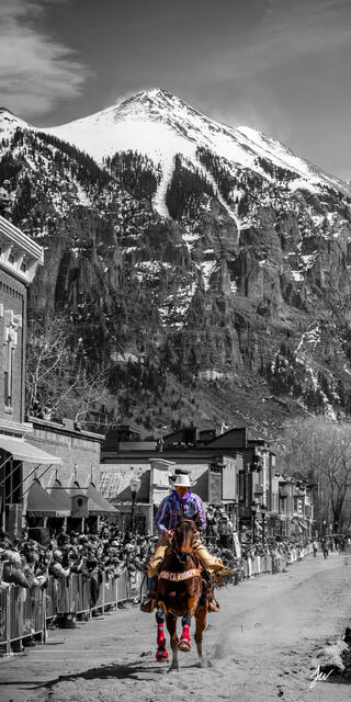 A cowboy rides through a snowy mountain setting in Telluride, Colorado during winter.